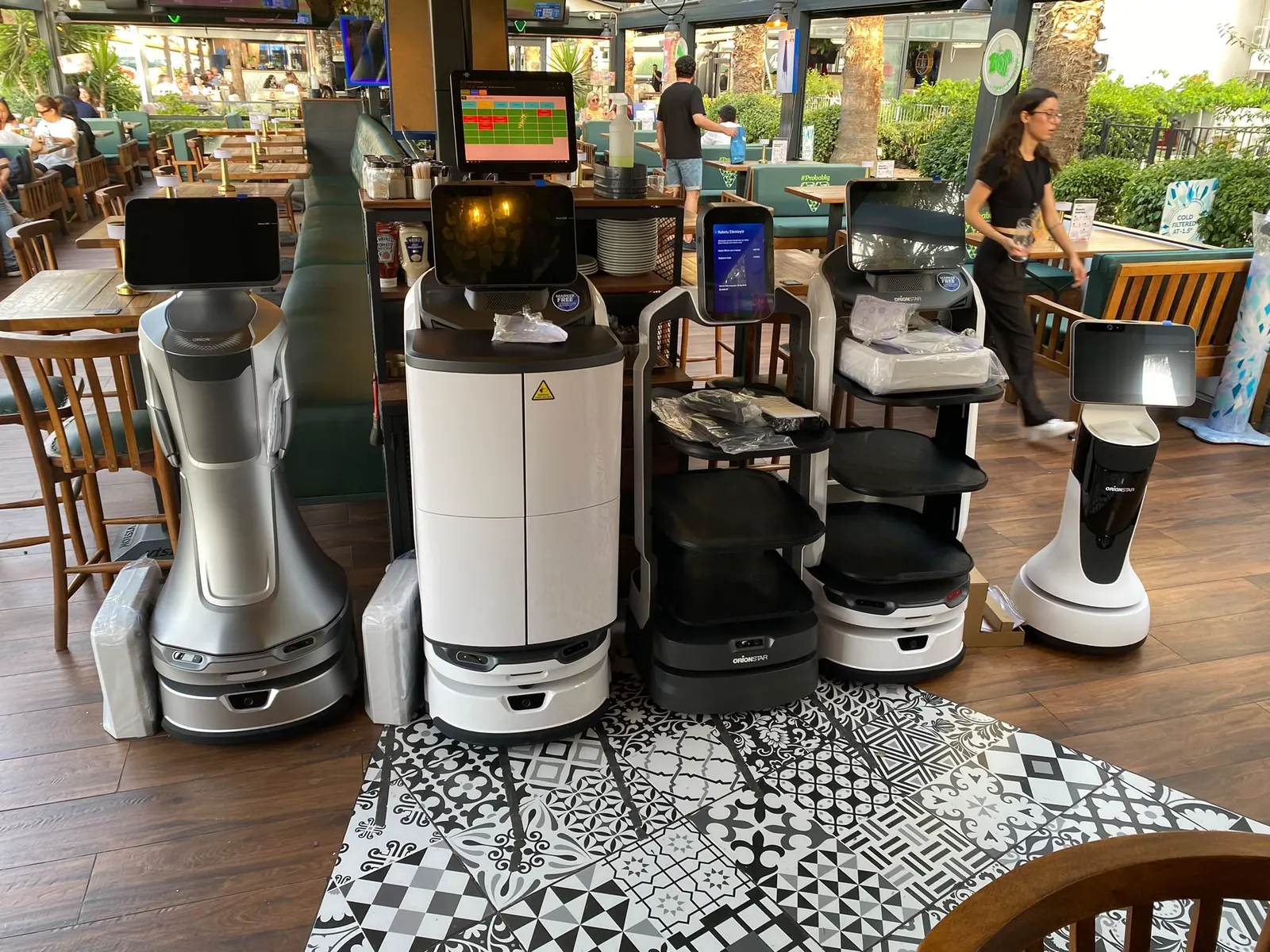 Restoranda yan yana duran karşılama, servis ve kapaklı teslimat robotları